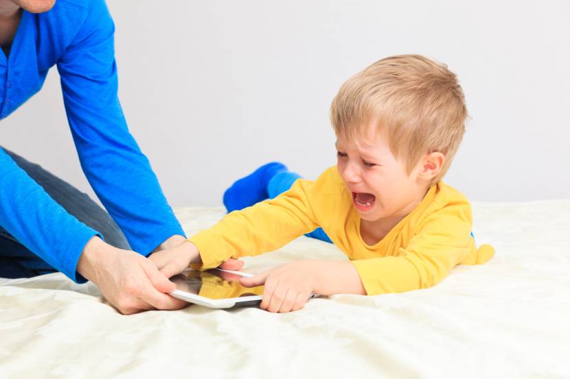 child upset because a tablet is being taken away from him