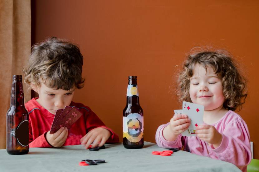 children playing cards with beer bottles on the table