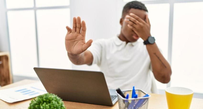 Man covering eyes while using computer